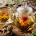 Flowering tea blooming inside a clear glass teapot, showcasing an artisan hand-tied tea blossom with colorful edible flowers in warm golden tea.