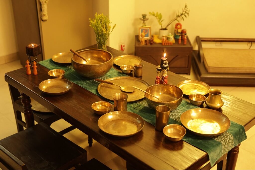 The Living Glow of Kansa: Why I Use Bengal’s Heritage Metal Every Day 2 A dinner table decorated with Kansa plates, bowls and spoons.