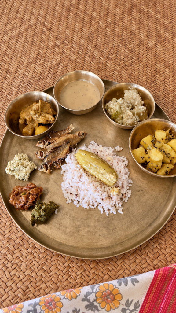A traditional Bengali meal of rice, small fried fish, vegetable dishes and three bhortas served on Paula’s aged kansa thali over woven matting.